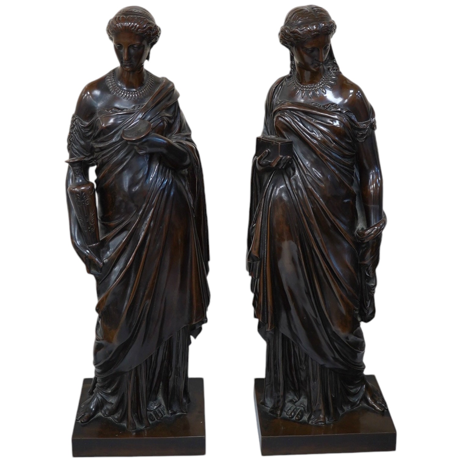 Eugene-Antoine Aizelin (French, 1820-1902). A pair of bronze classical robed figures of Pandora and Hebe, one holding a casket, the other a ewer and cup, having dark brown patination Height 50cm on square plinth base, si